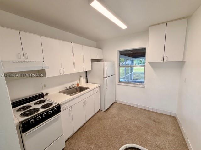 A kitchen with white cabinets, a white stove, a refrigerator, and carpeted flooring — 5608 Garfield St, Hollywood FL 33021, HOLLYWOOD, FL