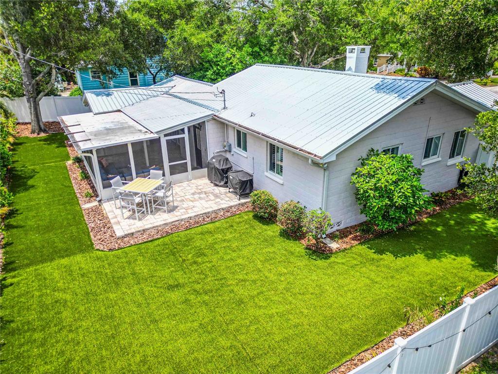 An aerial view of a house exterior featuring a metal roof, screened patio, and lawn — 131 VALENCIA DRIVE, DUNEDIN, FL