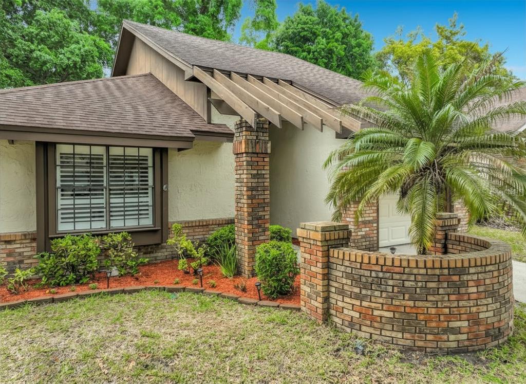 A single-story house exterior features a brick pillar, a wooden pergola, and a curved brick wall — 2966 GOLDEN VIEW LANE, ORLANDO, FL