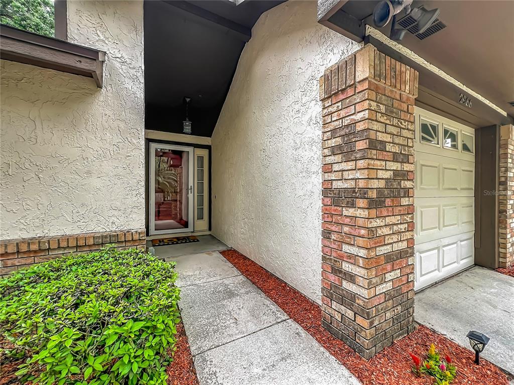 A concrete walkway leads to a front door with a brick pillar and stucco exterior — 2966 GOLDEN VIEW LANE, ORLANDO, FL