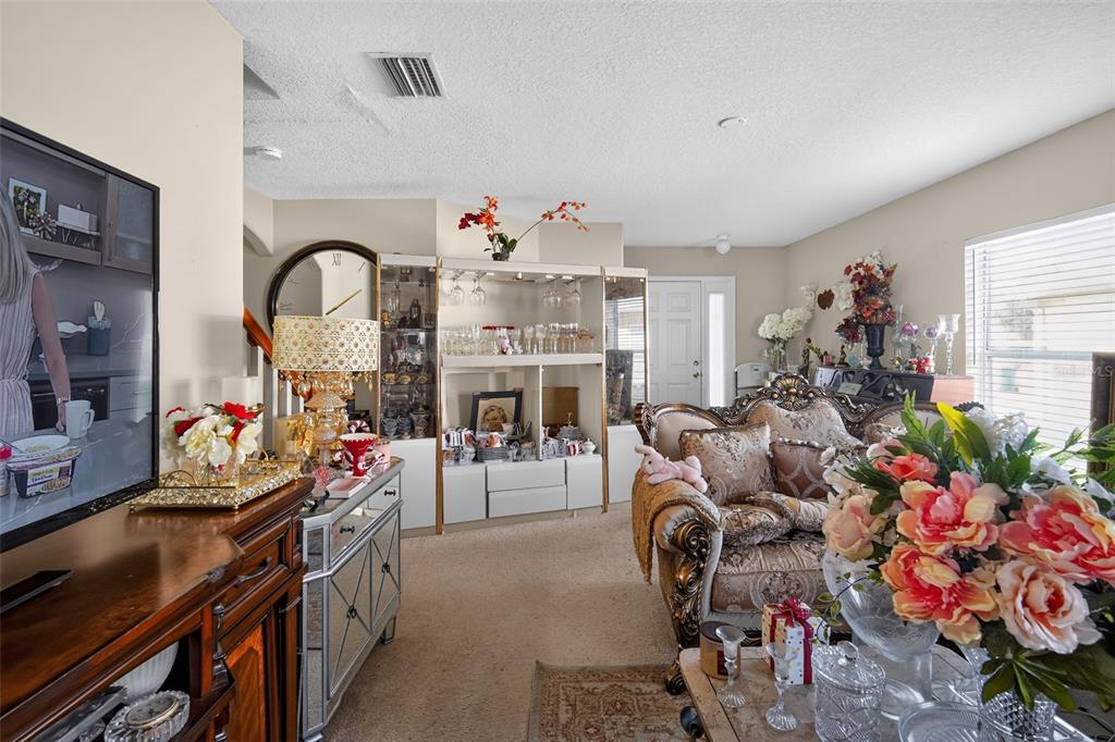 A living room features ornate furniture, a large display cabinet, and a television — 31417 TRIBOROUGH DRIVE, WESLEY CHAPEL, FL