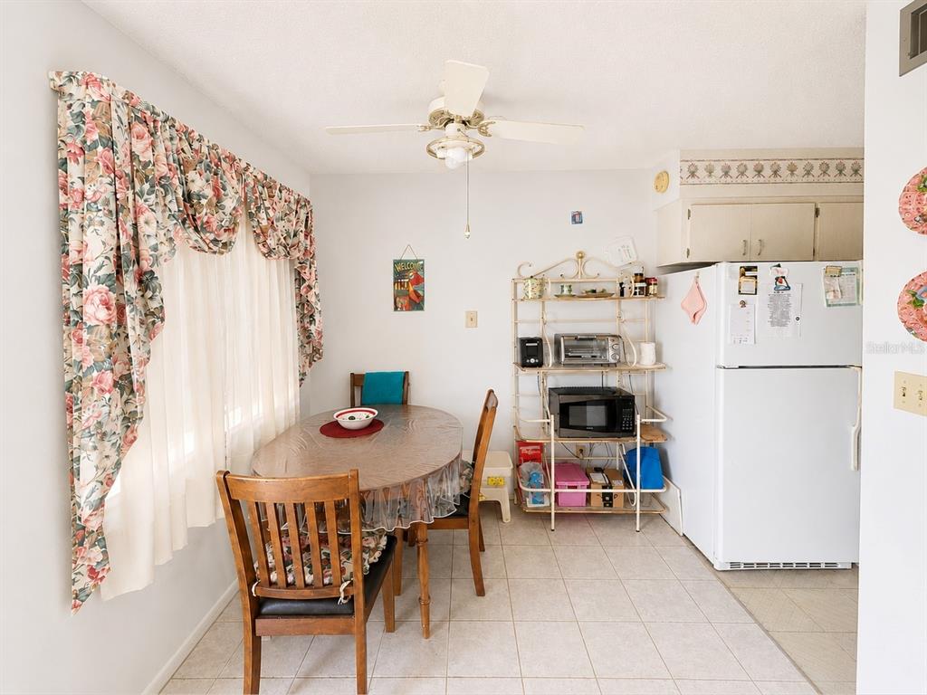 A dining area features a wooden table, chairs, a metal shelving unit, and a refrigerator — 250 ROSERY ROAD NW UNIT 328, LARGO, FL