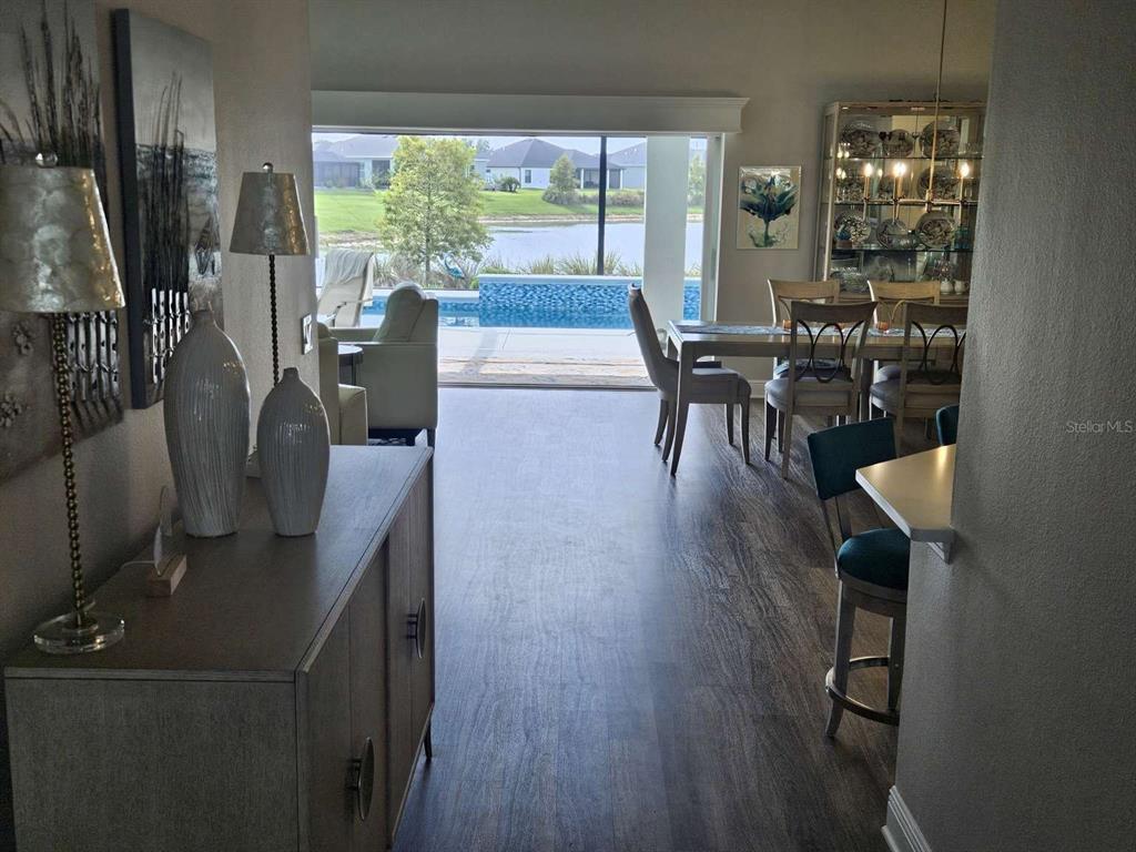 A view from a hallway looking into a dining area with a pool and lake view — 7602 FRANK DIPIETRO DRIVE, THE VILLAGES, FL