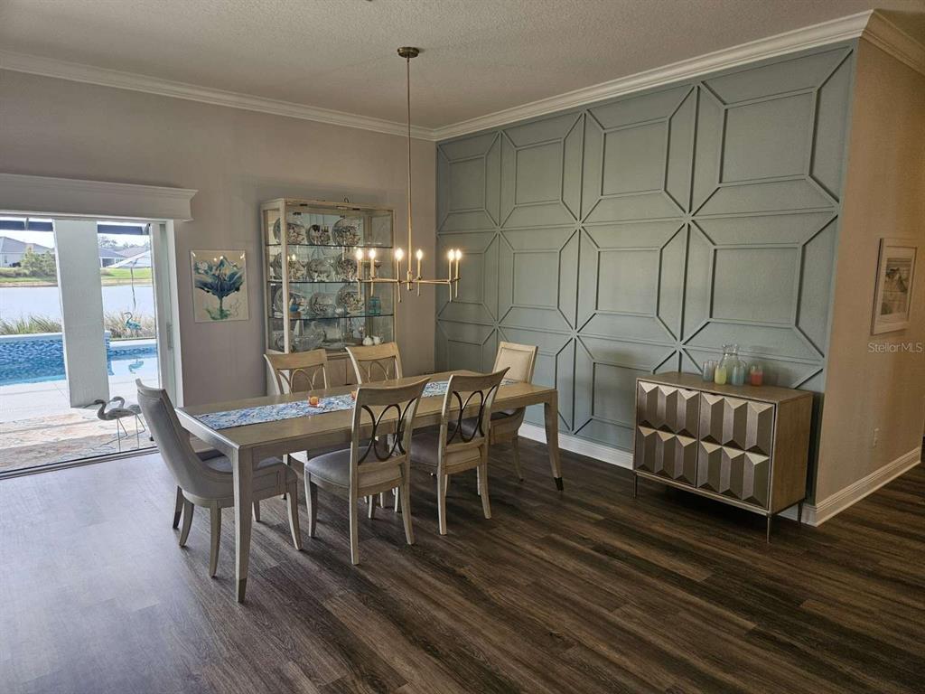 A dining room features a blue geometric accent wall, a glass cabinet, and a pool view — 7602 FRANK DIPIETRO DRIVE, THE VILLAGES, FL