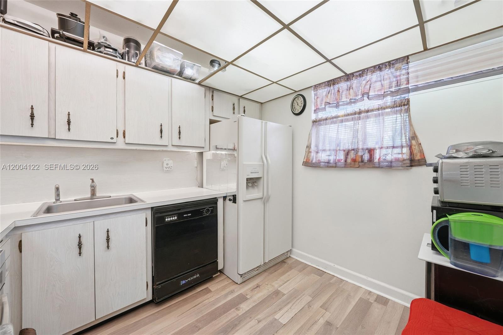 A kitchen features white cabinets, a black dishwasher, a white refrigerator, and a drop ceiling — 3190 Holiday Springs Blvd # 306, Margate FL 33063, MARGATE, FL