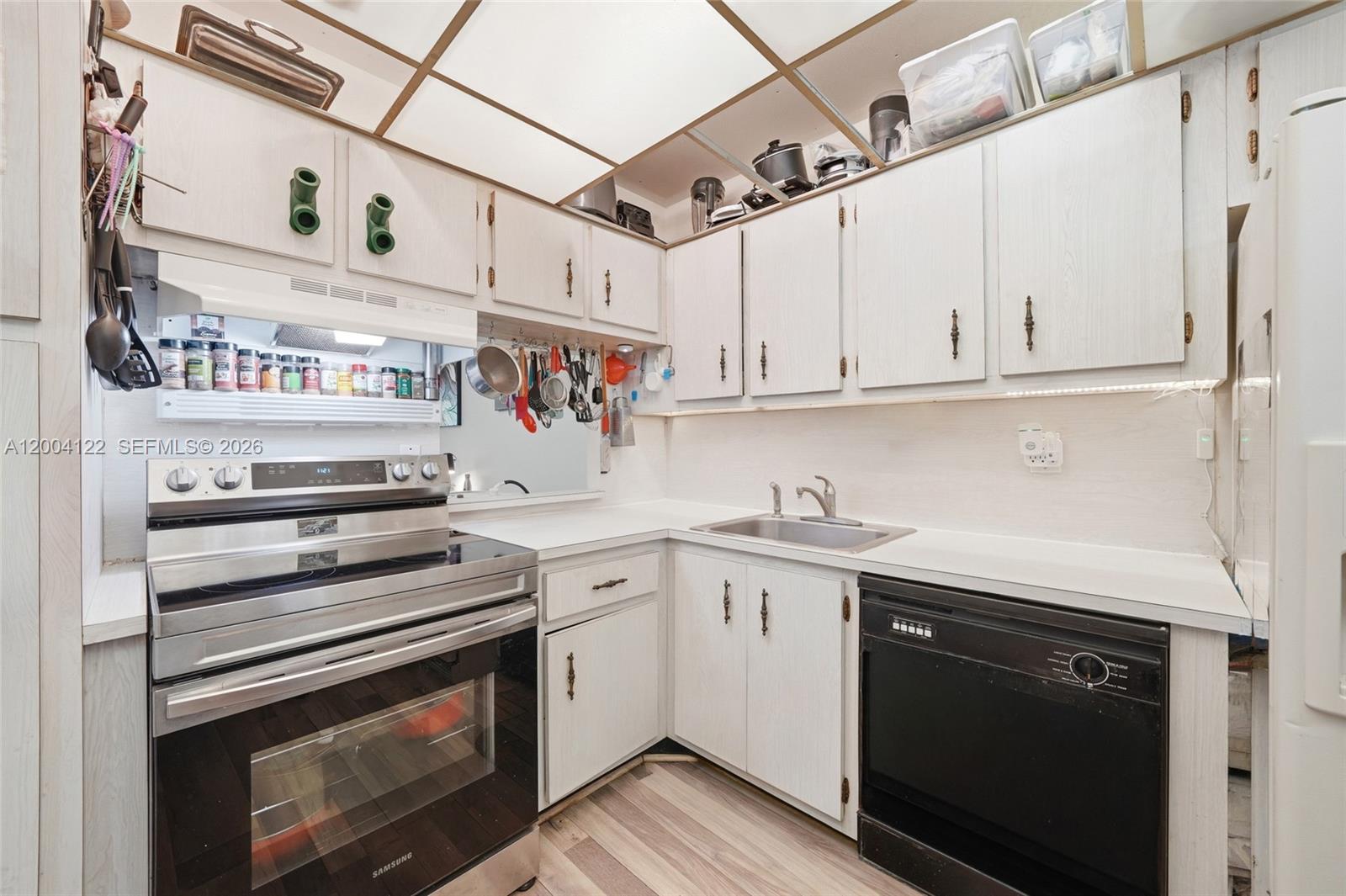 A kitchen features white cabinets, stainless steel appliances, a black dishwasher, and a drop ceiling — 3190 Holiday Springs Blvd # 306, Margate FL 33063, MARGATE, FL