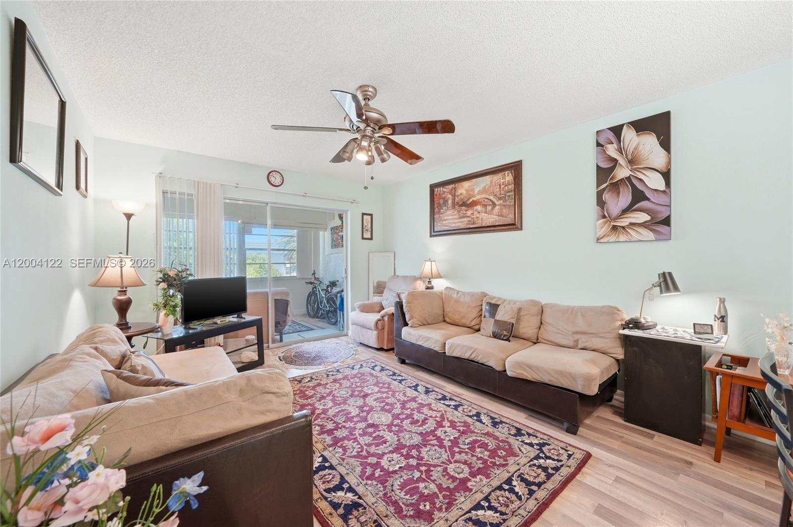 A living room features a beige sofa, a patterned area rug, and a sliding glass door — 3190 Holiday Springs Blvd # 306, Margate FL 33063, MARGATE, FL