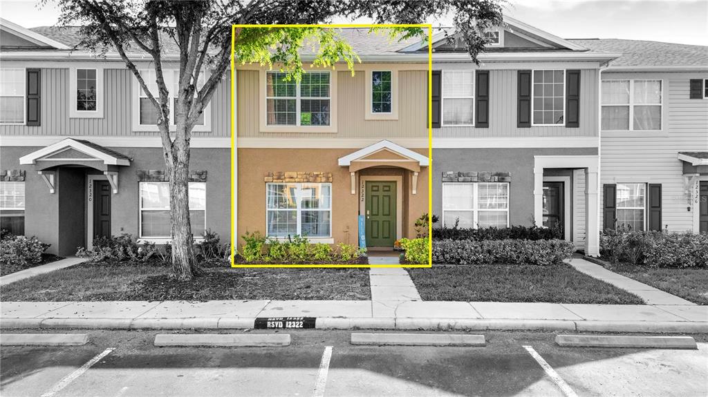A two-story townhouse exterior features a tan stucco facade, a green front door, and landscaping — 12322 FOXMOOR PEAK DRIVE, RIVERVIEW, FL