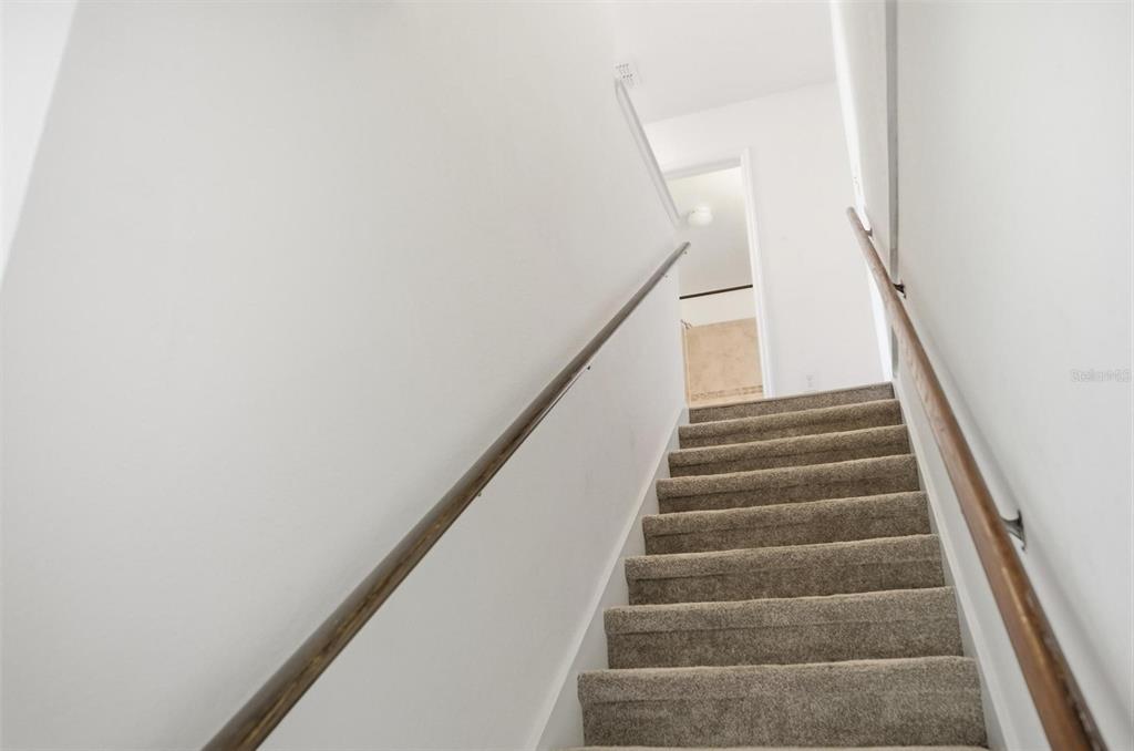 A carpeted staircase with wooden handrails leads to an upper landing — 4600 E MOODY BOULEVARD UNIT 1P, BUNNELL, FL