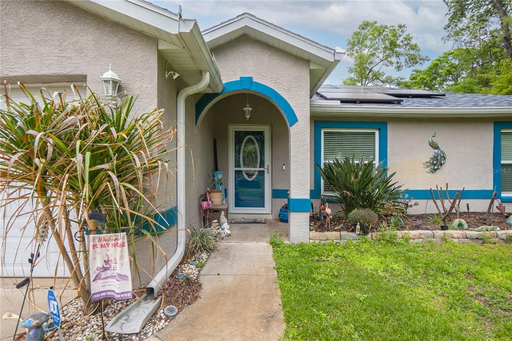 The exterior of a single-story house features a covered entryway, blue trim, and landscaping — 3956 S FERNPARK TERRACE, INVERNESS, FL