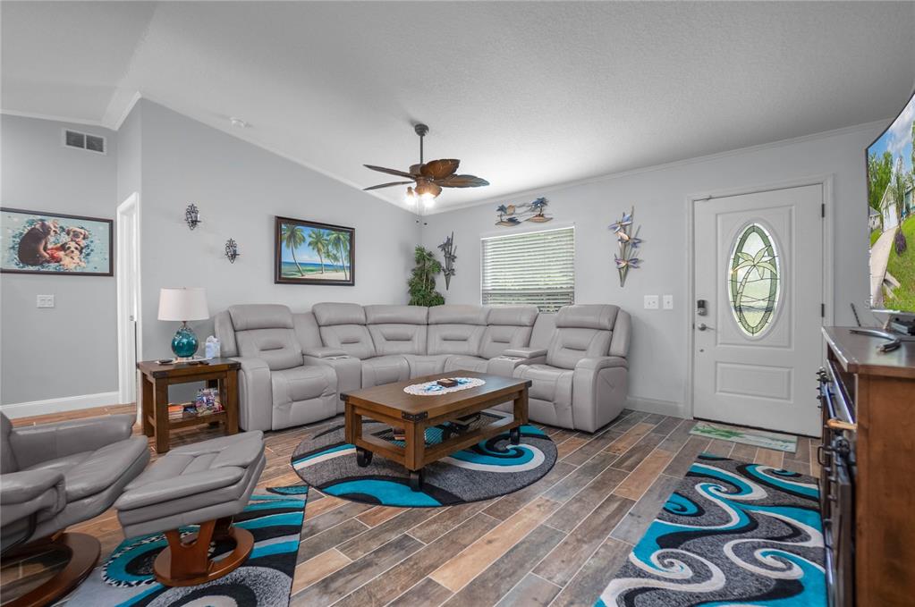 A living room features a gray sectional sofa, wood-topped coffee table, and patterned area rugs — 3956 S FERNPARK TERRACE, INVERNESS, FL