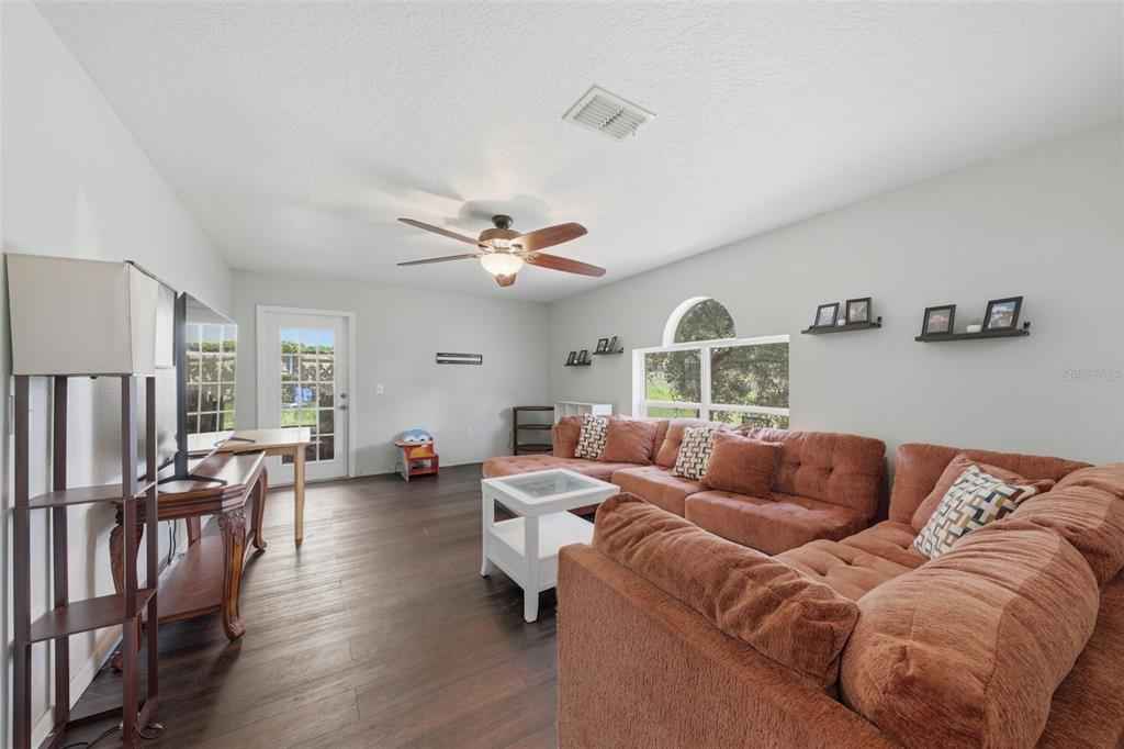 A living room features dark wood flooring, a large sectional sofa, and a ceiling fan — 800 MARIETTA LANE, EUSTIS, FL