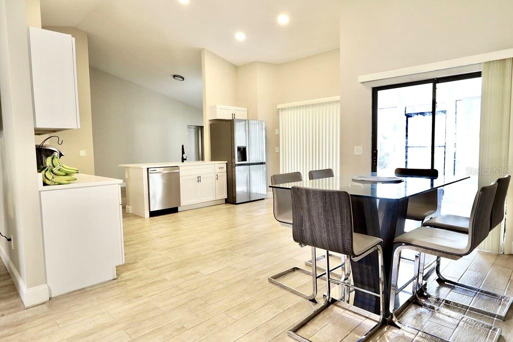 A kitchen and dining area feature white cabinetry, stainless steel appliances, and light wood-look flooring — 719 PINE TERRACE COURT, ALTAMONTE SPRINGS, FL