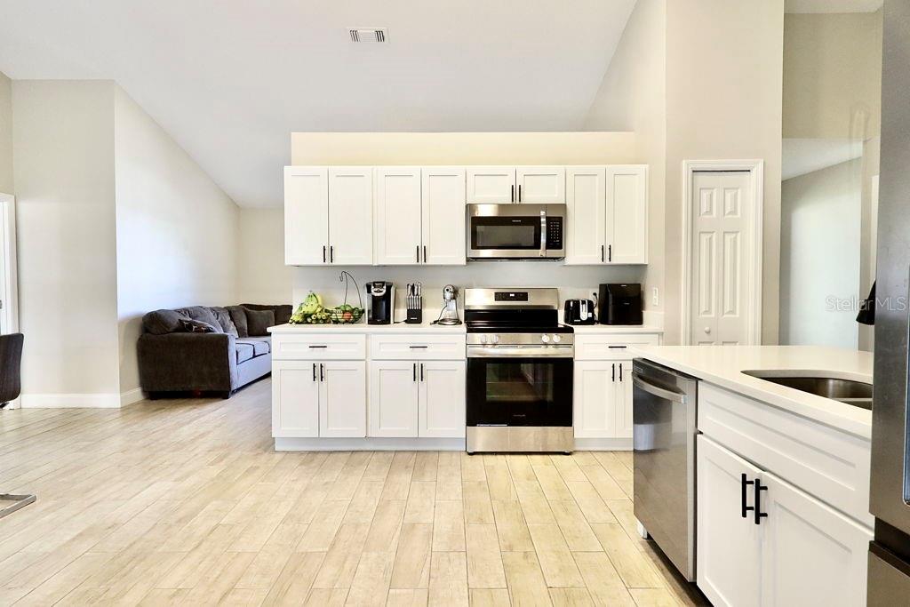 A kitchen with white cabinets, stainless steel appliances, and light wood-look flooring — 719 PINE TERRACE COURT, ALTAMONTE SPRINGS, FL