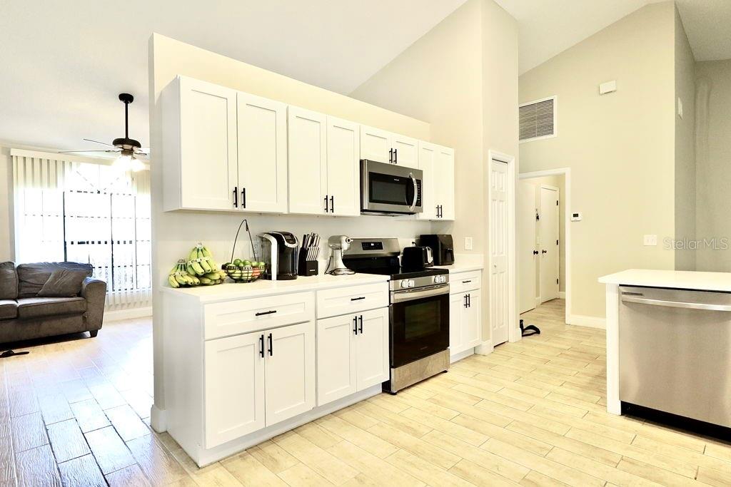A kitchen features white cabinets, stainless steel appliances, and light-colored wood-look tile flooring — 719 PINE TERRACE COURT, ALTAMONTE SPRINGS, FL