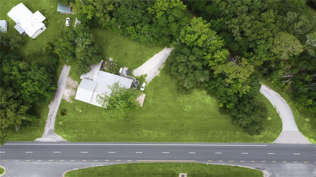 An aerial view shows a house with a metal roof, two driveways, and surrounding trees — 7220 NE US HIGHWAY 301, HAWTHORNE, FL