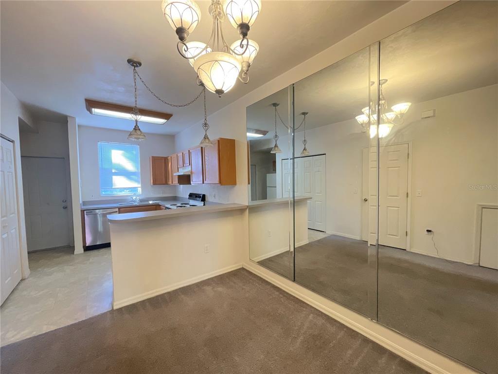 A dining area with a mirrored wall, a chandelier, and an adjacent kitchen with cabinets — 3930 SW 20TH AVENUE UNIT 1902, GAINESVILLE, FL