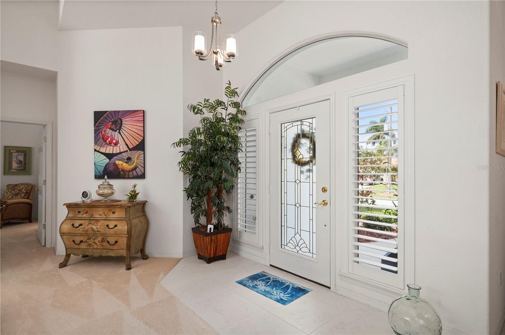 An entryway features a white front door with sidelights, a potted plant, and a chest — 5018 CAPTIVA COURT, PUNTA GORDA, FL