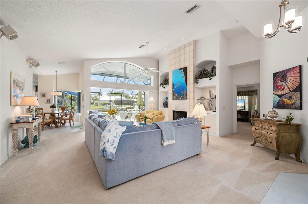 A living room with a blue sectional sofa, fireplace, and large windows overlooking a pool — 5018 CAPTIVA COURT, PUNTA GORDA, FL