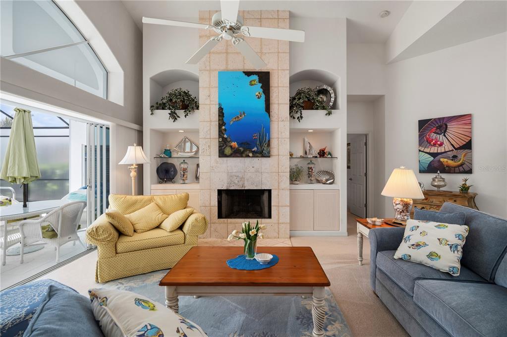 A living room features a stone fireplace, built-in shelving, a ceiling fan, and blue furniture — 5018 CAPTIVA COURT, PUNTA GORDA, FL