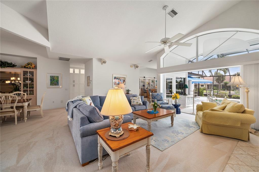 A living room with a blue sectional, yellow armchair, and large windows overlooking a pool — 5018 CAPTIVA COURT, PUNTA GORDA, FL
