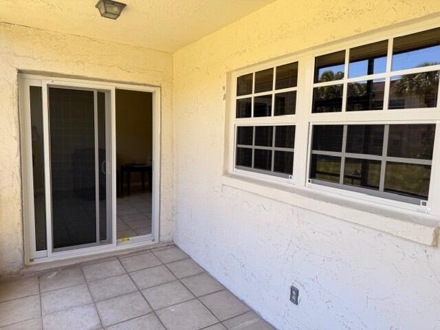 A patio with tiled flooring, a sliding glass door, and a window with grid panes — 3001 Linton Boulevard # 107c, Delray Beach FL 33445, DELRAY BEACH, FL