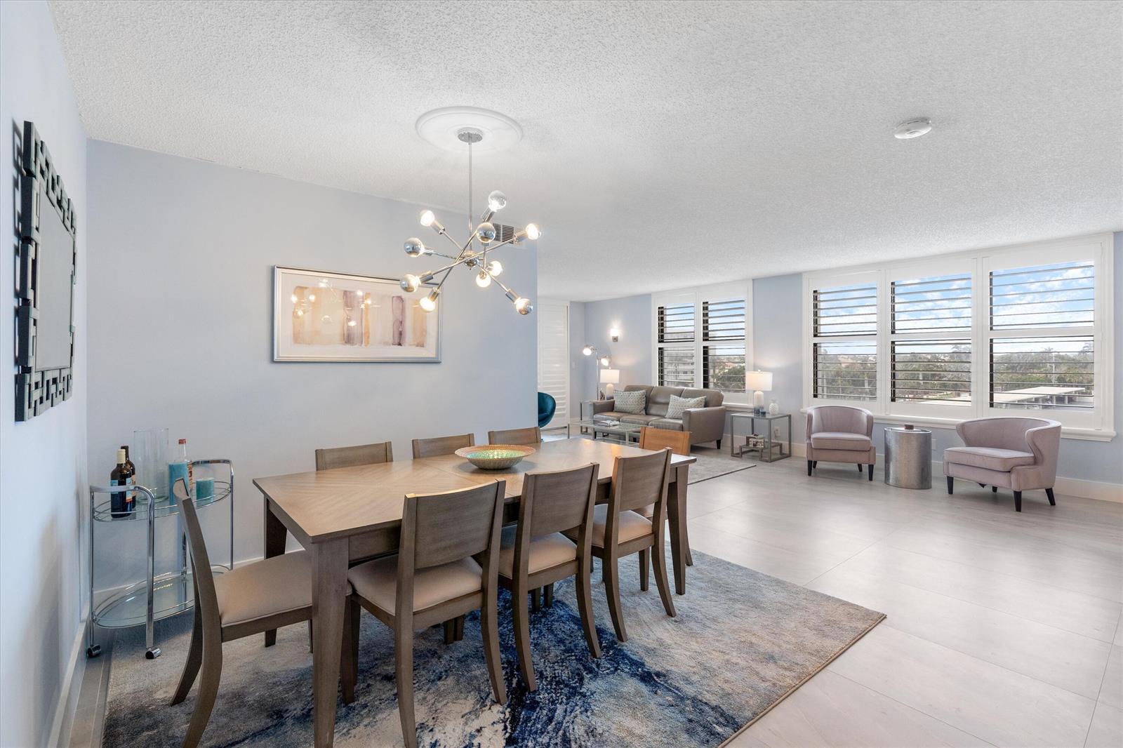 A dining area with a modern chandelier and a living room with large windows — 3115 S Ocean Boulevard # 302, Highland Beach FL 33487, HIGHLAND BEACH, FL