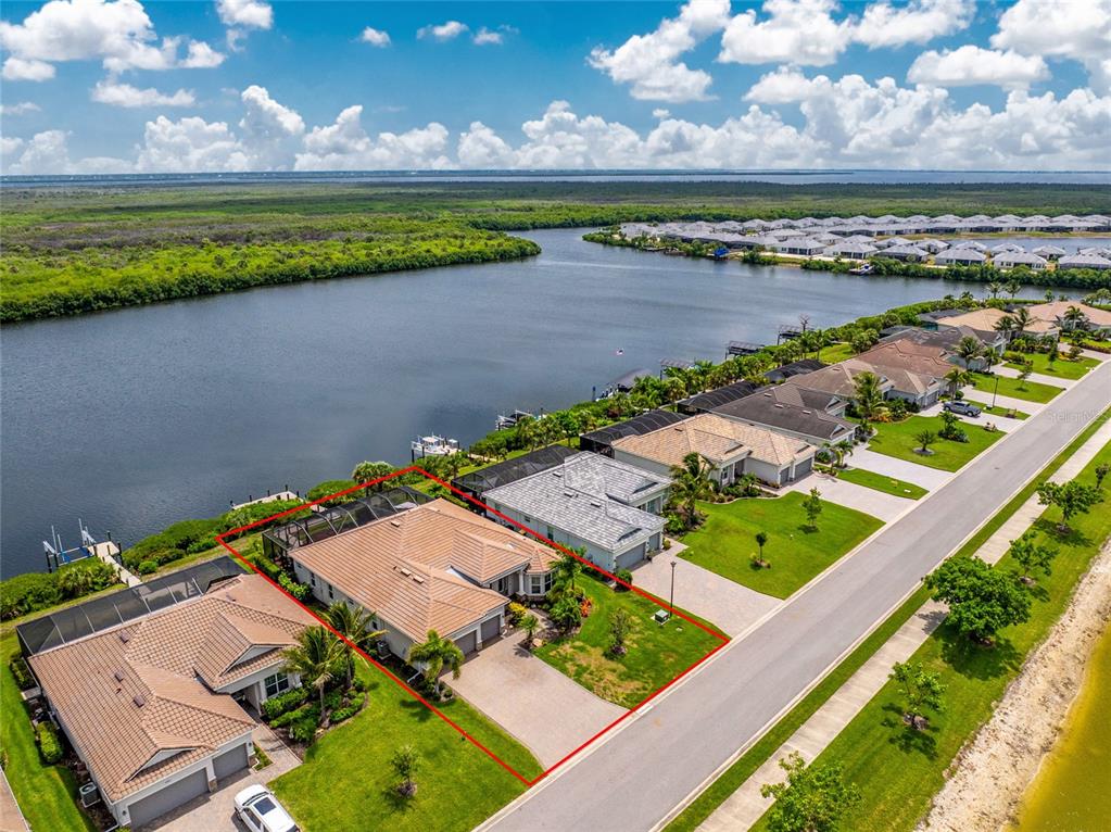 An aerial view shows a waterfront house with a screened pool and tile roof — 15248 SPANISH POINT DRIVE, PORT CHARLOTTE, FL