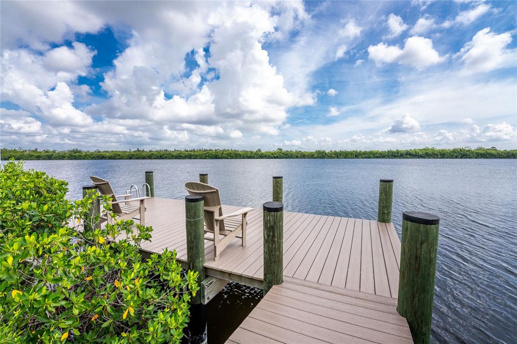 A wooden dock with two chairs extends over a calm body of water — 15248 SPANISH POINT DRIVE, PORT CHARLOTTE, FL