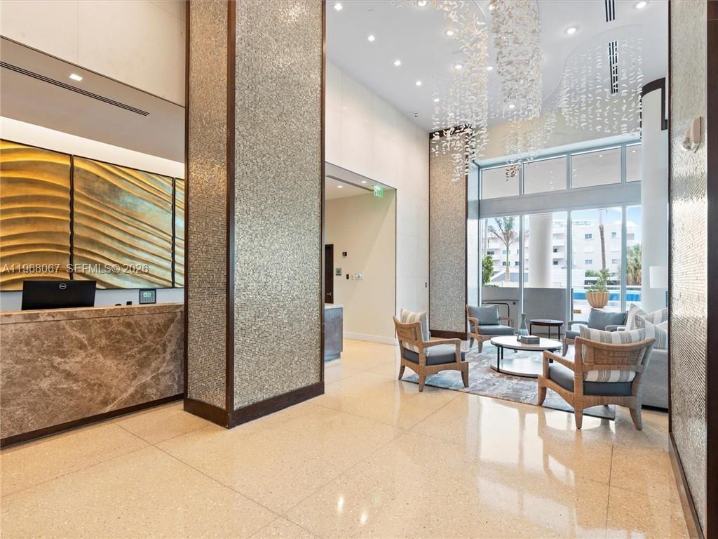 A modern lobby features a marble reception desk, tiled columns, and a seating area — 6799 Collins Ave # 301, Miami Beach FL 33141, MIAMI BEACH, FL