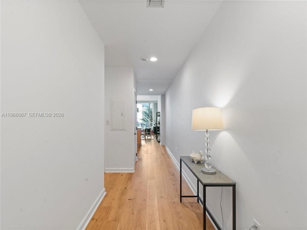 A narrow hallway with light wood flooring leads toward a bright living area — 6799 Collins Ave # 301, Miami Beach FL 33141, MIAMI BEACH, FL