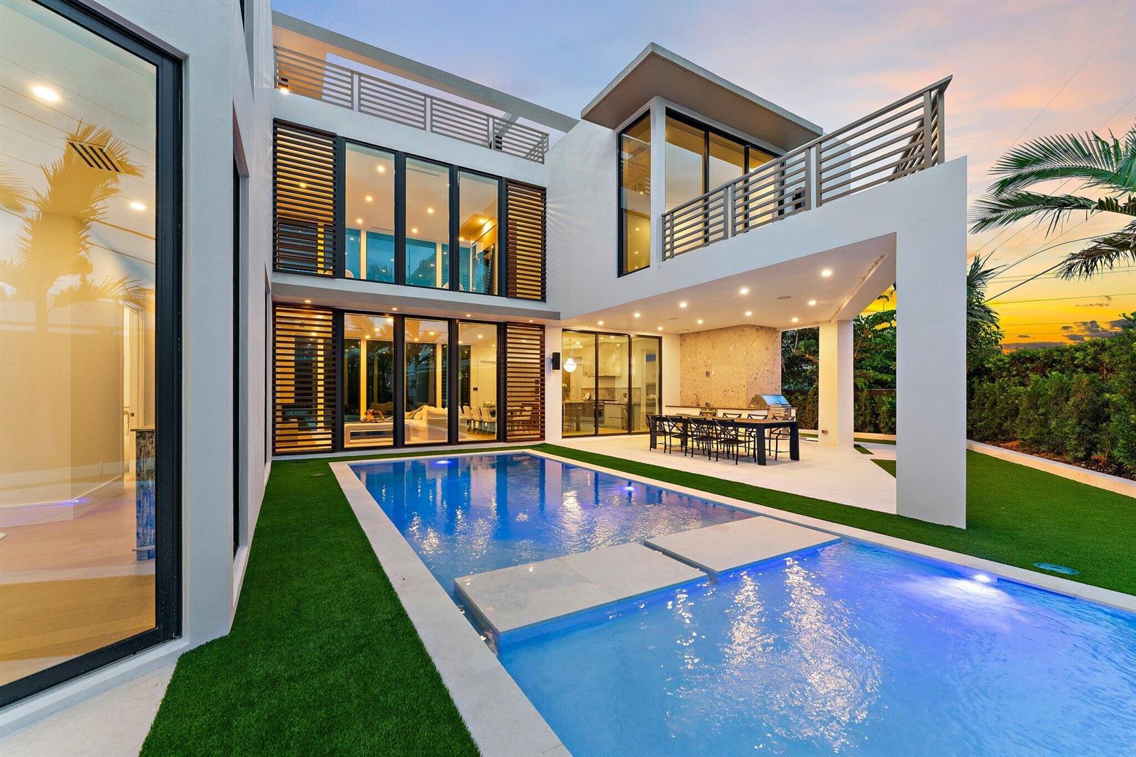 A modern two-story house features a swimming pool, outdoor dining area, and a balcony — 390 Jupiter Lane, Juno Beach FL 33408, JUNO BEACH, FL
