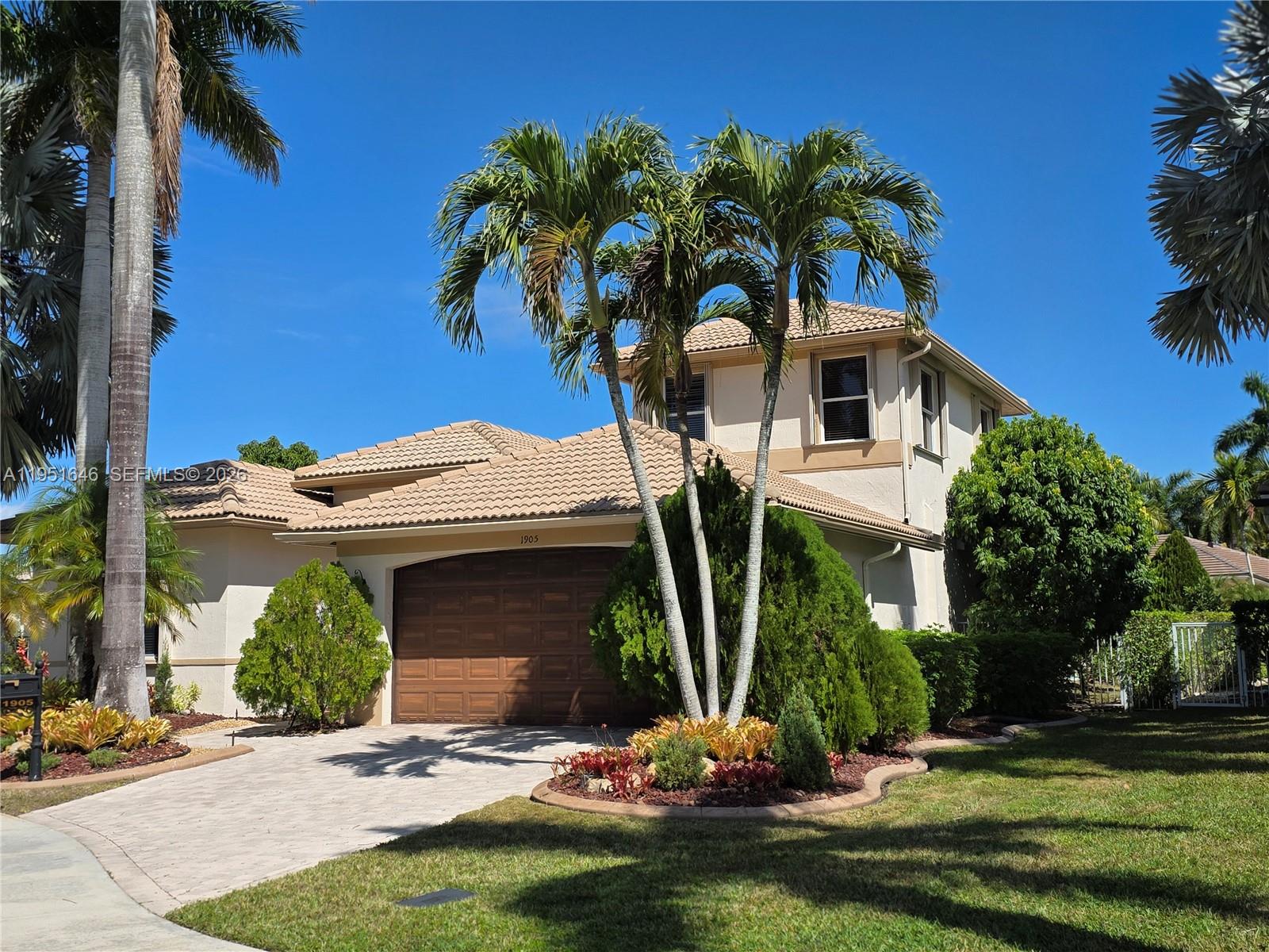 A two-story house with a tiled roof, a brown garage door, and palm trees — 1905 Harbor View Cir, Weston FL 33327, WESTON, FL