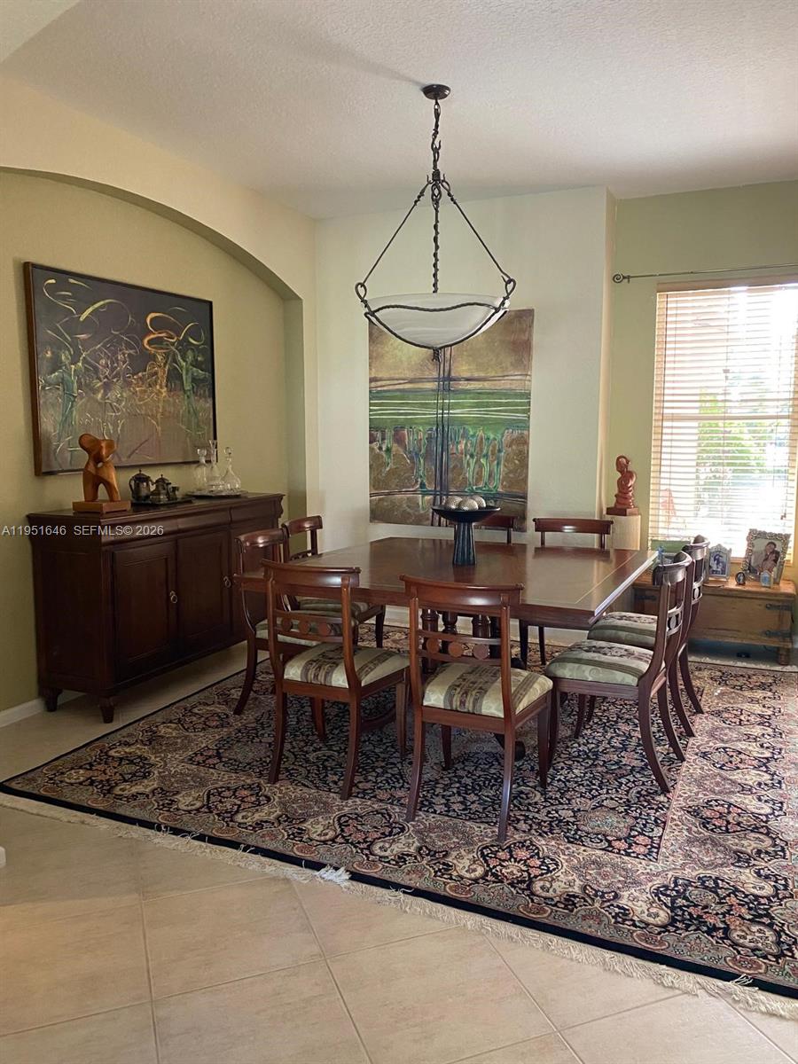 A dining room features a wooden table and chairs set atop a patterned area rug — 1905 Harbor View Cir, Weston FL 33327, WESTON, FL
