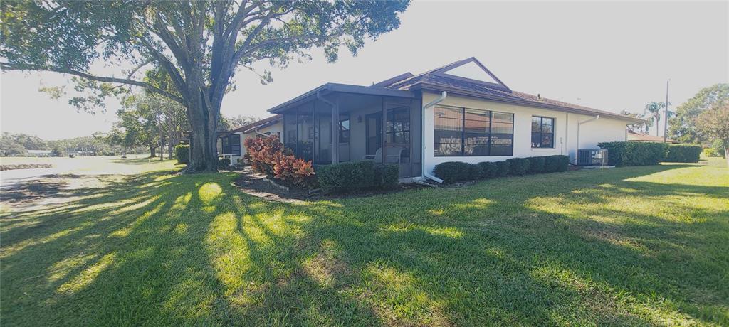 A single-story house with a screened-in porch, a large tree, and a grassy yard — 3422 LORI LANE UNIT 3422, NEW PORT RICHEY, FL