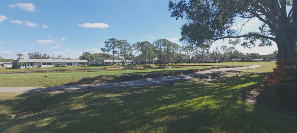 A paved patio area sits in front of a white building with a covered entryway — 3422 LORI LANE UNIT 3422, NEW PORT RICHEY, FL