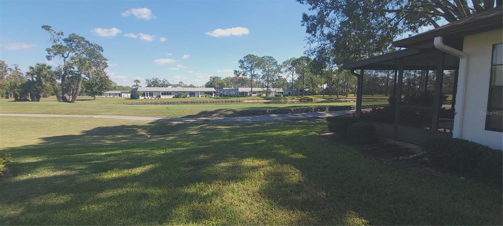 A white exterior wall features a single door, a window with shutters, and landscaping — 3422 LORI LANE UNIT 3422, NEW PORT RICHEY, FL