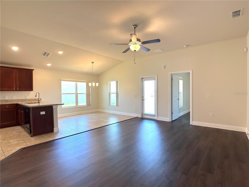 An open-concept living area features dark wood flooring, a kitchen with tile, and a ceiling fan — 1378 LEGATTO LOOP, DUNDEE, FL