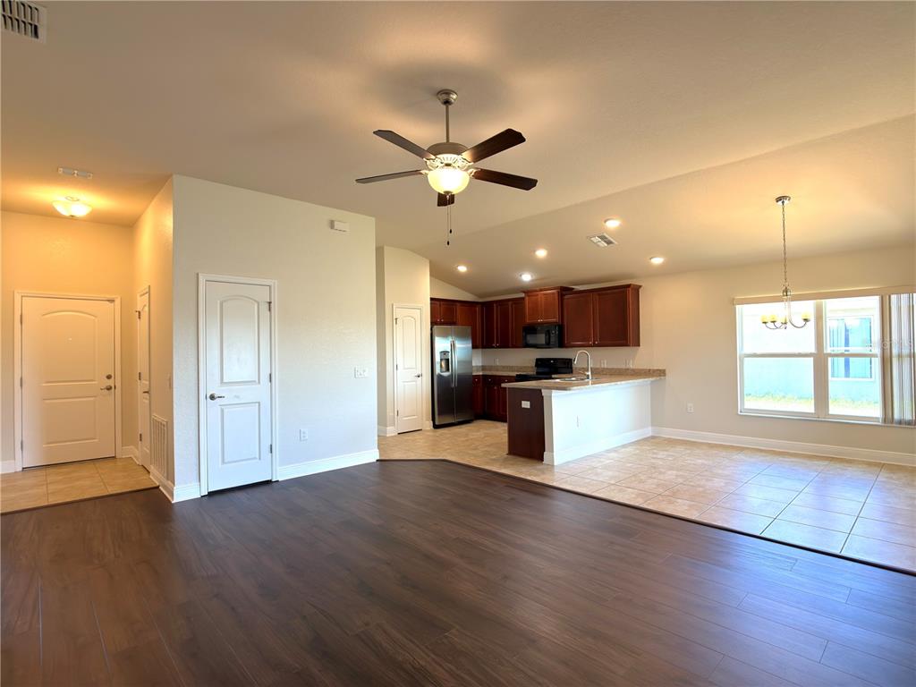 An open-concept living area features dark wood flooring, a kitchen with brown cabinets, and tile — 1378 LEGATTO LOOP, DUNDEE, FL