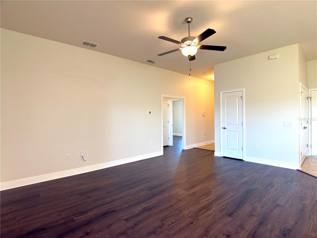 A spacious room with dark wood-look flooring, a ceiling fan, and white interior doors — 1378 LEGATTO LOOP, DUNDEE, FL