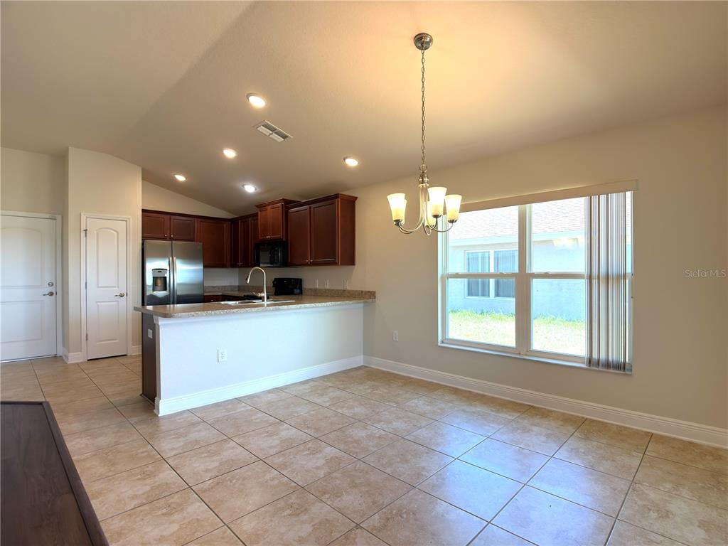 A kitchen with dark wood cabinets and a breakfast bar overlooks a tiled dining area — 1378 LEGATTO LOOP, DUNDEE, FL