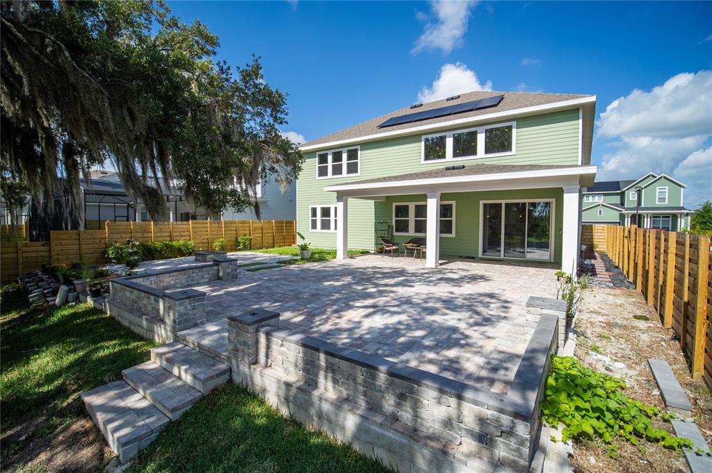 A two-story green house features a paved patio with stone retaining walls and stairs — 6236 TRAILBLAZE BEND, ST CLOUD, FL