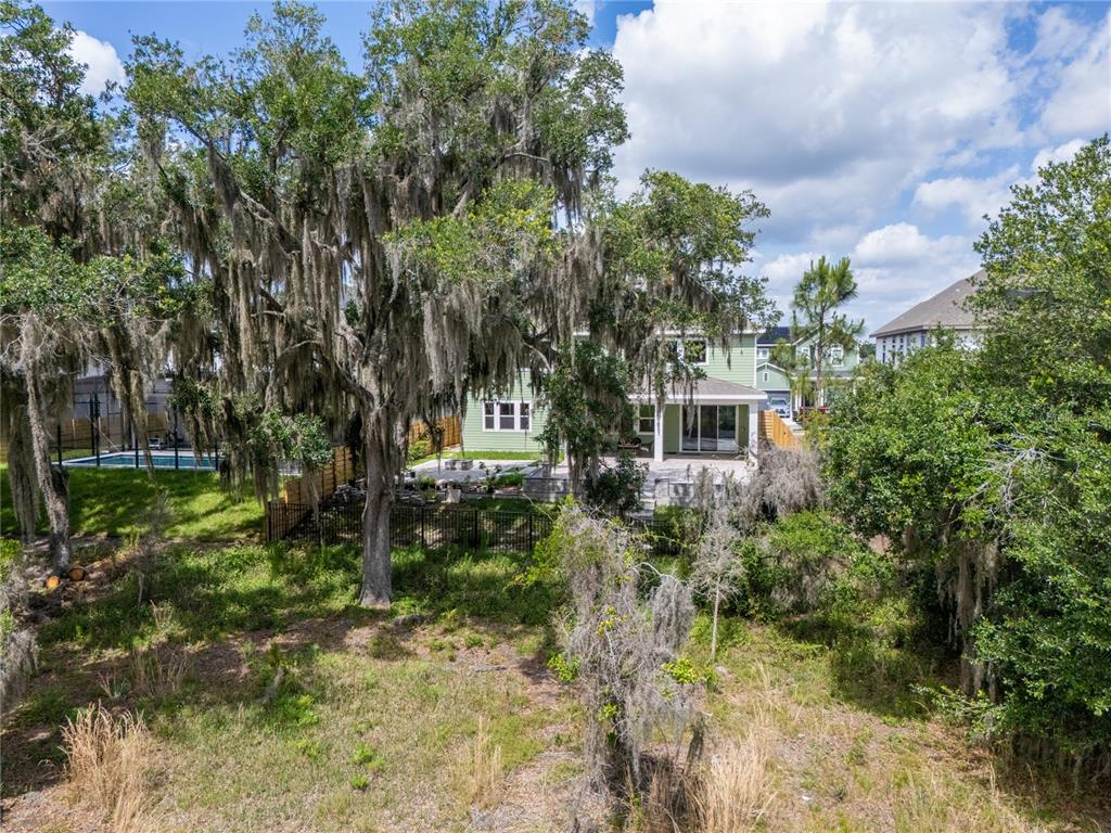 A two-story house with a patio and pool sits behind a large, moss-covered oak tree — 6236 TRAILBLAZE BEND, ST CLOUD, FL