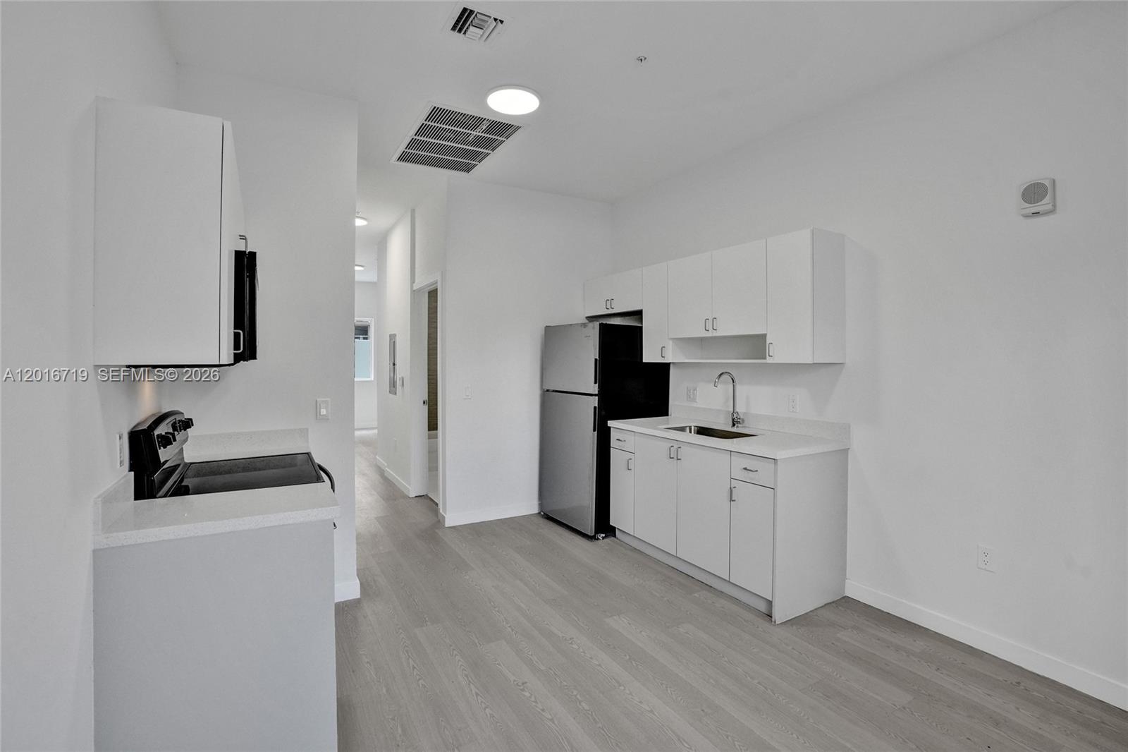 A kitchen features white cabinets, stainless steel appliances, and light wood-look flooring — 1567 NW 1st St # 2, Miami FL 33125, MIAMI, FL