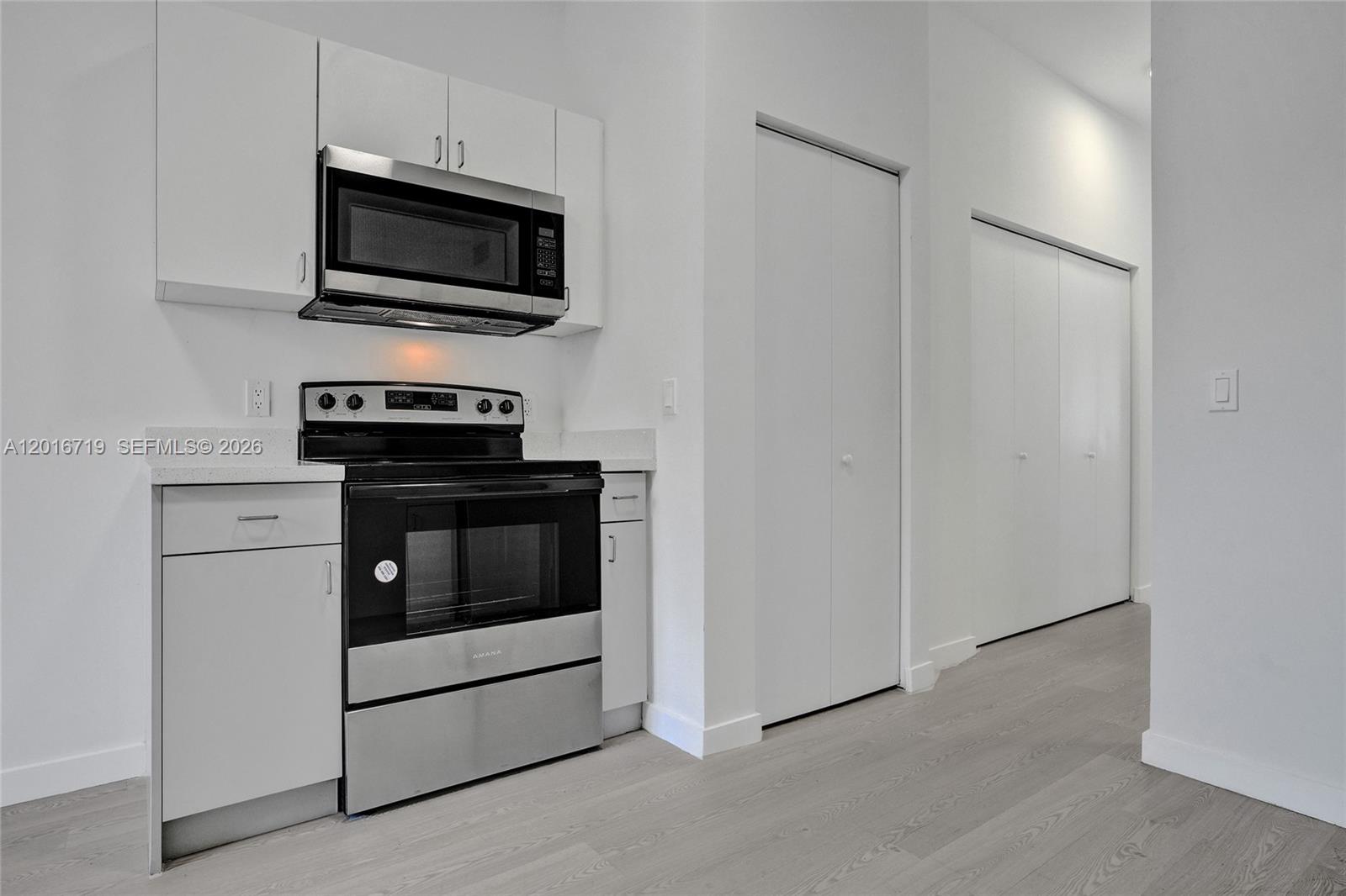 A kitchen features white cabinets, stainless steel appliances, and light wood-look flooring — 1567 NW 1st St # 2, Miami FL 33125, MIAMI, FL