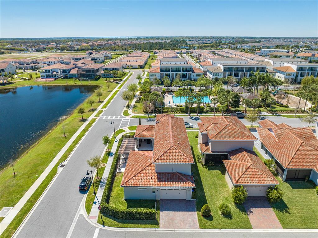 An aerial view shows suburban houses with red-tiled roofs near a lake and pool — 9406 MERE PARKWAY, ORLANDO, FL