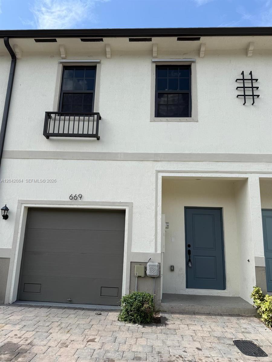 The exterior of a two-story townhouse features a garage, a front door, and two windows — 669 SW 11th St, Florida City FL 33034, FLORIDA CITY, FL