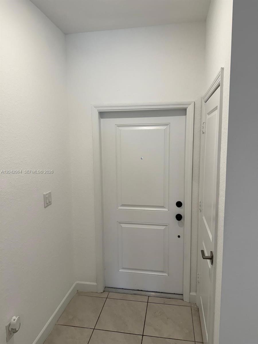 An entryway features a white front door, a side closet door, and light-colored tile flooring — 669 SW 11th St, Florida City FL 33034, FLORIDA CITY, FL