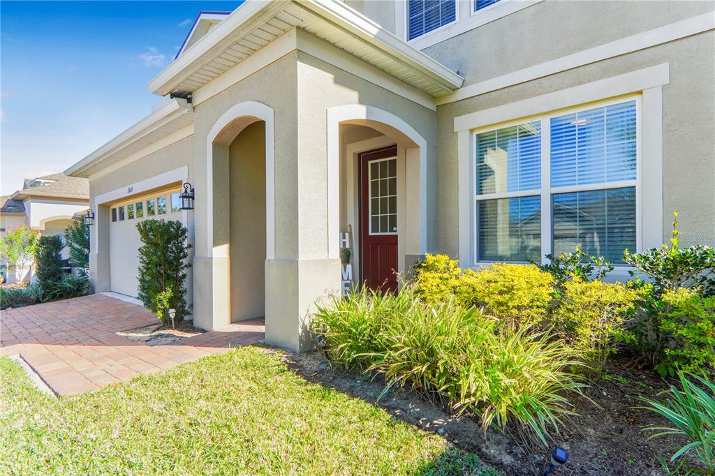 The exterior of a house features a red front door, brick walkway, and landscaping — 2045 SUWANNEE BANKS STREET, CLERMONT, FL
