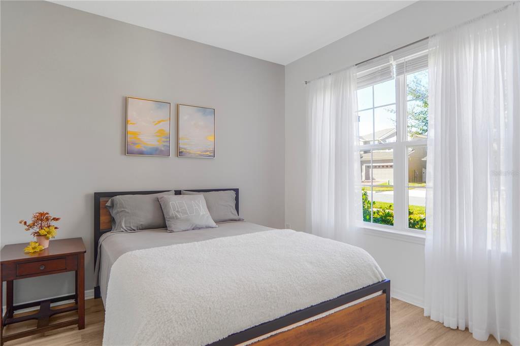 A bedroom features a bed with grey bedding, a wooden side table, and a window — 2045 SUWANNEE BANKS STREET, CLERMONT, FL